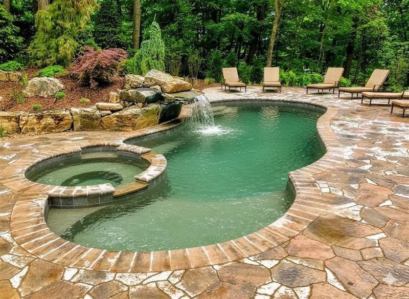 A freeform pool with a hot tub and waterfall - AB Premium