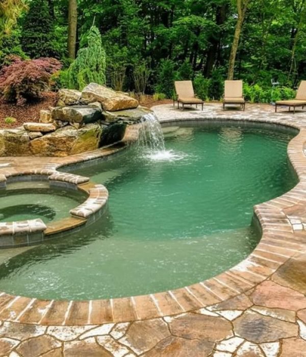 A freeform pool with a hot tub and waterfall - AB Premium